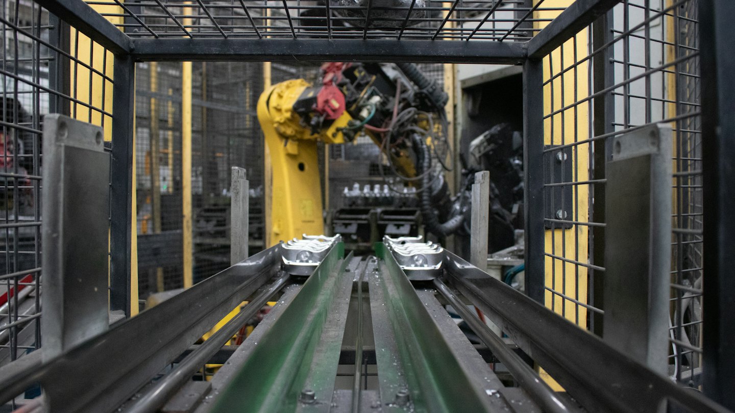 Braccio robotico al lavoro su una linea di produzione con nastri trasportatori.