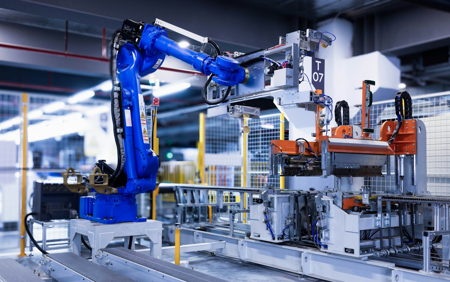 Braccio robotico blu che lavora su una linea di assemblaggio in una fabbrica.